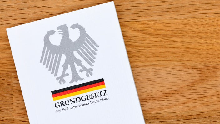 Das deutsche Grundgesetz liegt auf einem Untergrund aus Holz.