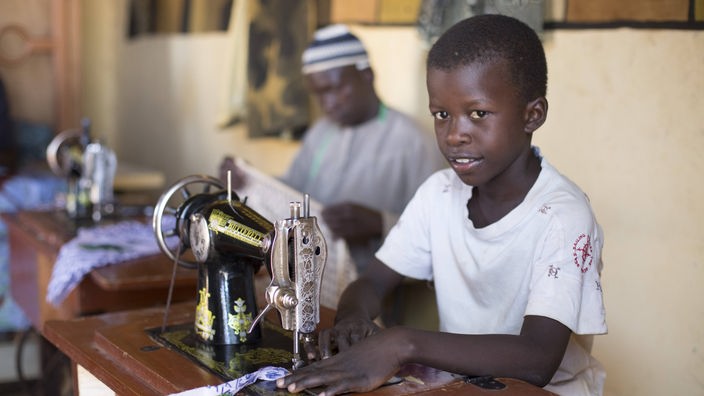 Junge an einer Nähmaschine in einer Fabrik in Mali
