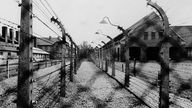 Schwarz-Weiß-Bild: Blick auf den Elektrozaun zwischen den Blöcken des ehemaligen Konzentrationslagers Auschwitz