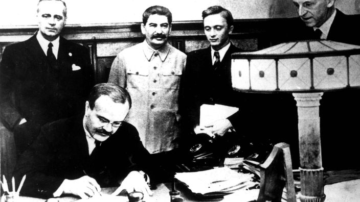 Schwarz-weiß-Bild: Der deutsche Reichsminister des Auswärtigen Joachim von Ribbentrop unterzeichnet den deutsch-sowjetischen Nichtangriffspakt.
