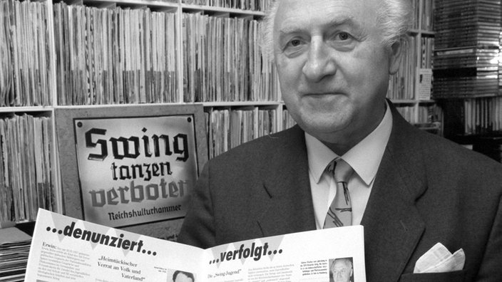 Ein Mann hält eine Zeitung mit Infos über Jugendliche in deutschen Konzentrationslagern hoch | Bildquelle: picture-alliance / dpa Ein Mann hält eine Zeitung mit Infos über Jugendliche in deutschen Konzentrationslagern hoch