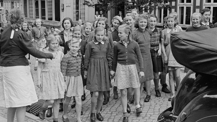 Mädchen stehen in einer Reihe nebeneinander. | Bildquelle: akg Mädchen stehen in einer Reihe nebeneinander.