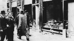 Passanten laufen an einem zerstörten jüdischen Geschäft vorbei.