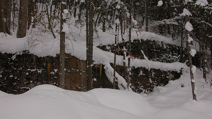 Unscheinbare Fundamentreste in einem verschneiten Wald markieren noch Hitlers ehemaligen Berghof. | Bildquelle: Gregor Delvaux de Fenffe Unscheinbare Fundamentreste in einem verschneiten Wald markieren noch Hitlers ehemaligen Berghof.
