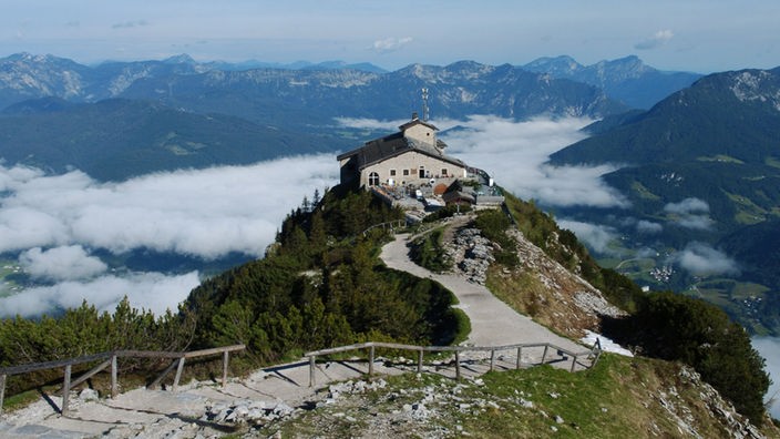 Das Kehlsteinhaus: Adolf Hitlers ehemaliges Teehaus bei Berchtesgaden. Ein Weg führt zum Haus auf einem Felssporn. Im Hintergrund Panoramalandschaft der Berchtesgadener Alpen.