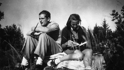 Hans und Sophie Scholl sitzen auf einer Bergwiese. Sophie liest in einem Buch.