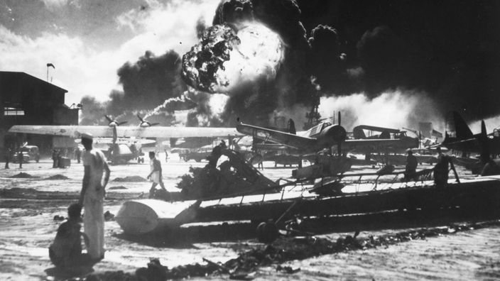 Schwarzweiß-Bild: Japanische Kampfflugzeuge greifen den US-Flottenstützpunkt Pearl Harbor an.