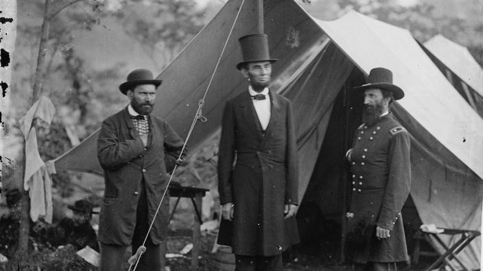 Lincoln steht mit zwei Untergebenen vor einem Zelt im Feldlager,