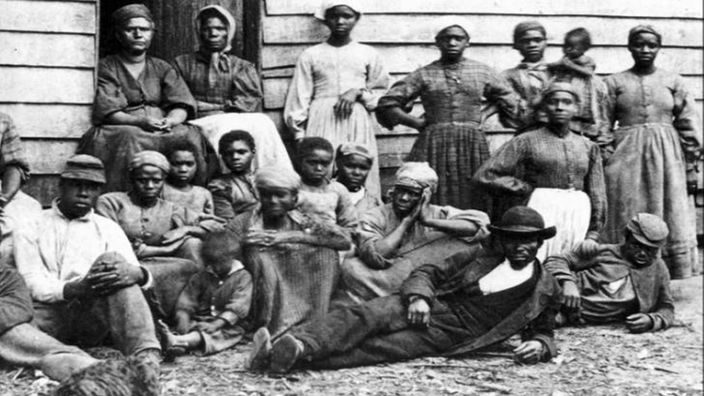 Archivfoto: Sklaven vor einer Holzhütte.