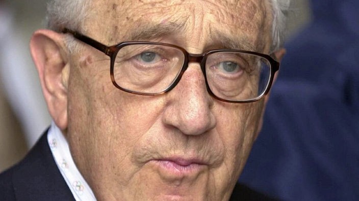 Porträt von Henry Kissinger, ein älterer Mann mit grauen Haaren und Hornbrille.