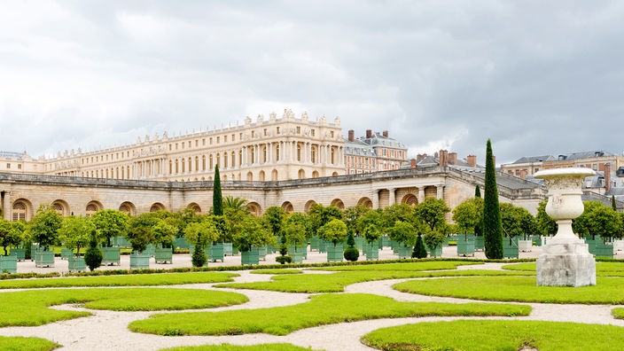 Prächtige barocke Gartenanlage mit Schloss Versailles im Hintergrund.