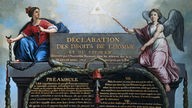 Tafel, überschrieben mit „Erklärung der Menschen und Bürgerrechte“ auf Französisch, umrahmt von zwei allegorischen Frauengestalten.