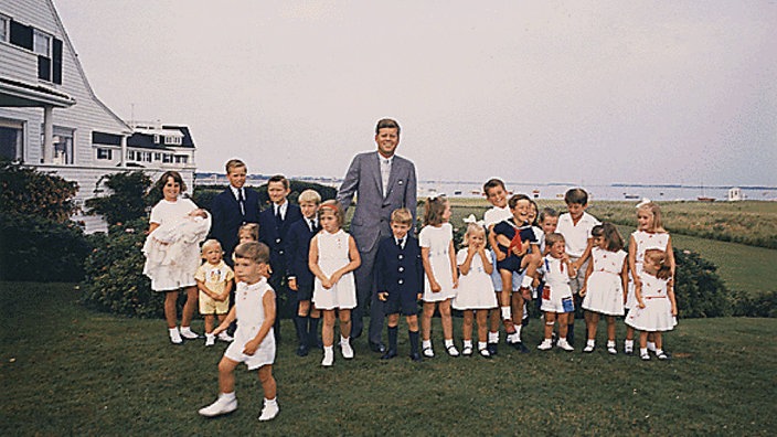 John F. Kennedy im Kreise junger Familienmitglieder vor dem Familiernanwesen in Hyannis Port | Bildquelle: Imago/Zuma Press John F. Kennedy im Kreise junger Familienmitglieder vor dem Familiernanwesen in Hyannis Port