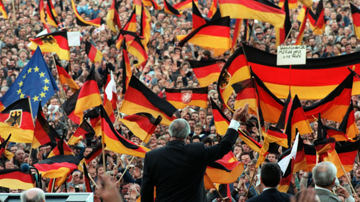 Helmut Kohl vor Deutschland-Flaggen 1990.