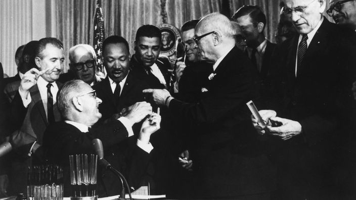 Schwarzweiß-Aufnahme: Präsident Johnson und Martin Luther King während der Unterzeichnung des Bürgerrechtsgesetzes