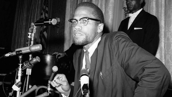 Schwarzweiß-Aufnahme: Malcolm X vor Mikrofonen