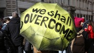 Regenschirm mit der Aufschrift "We shall overcome"