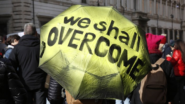 Regenschirm mit der Aufschrift "We shall overcome"