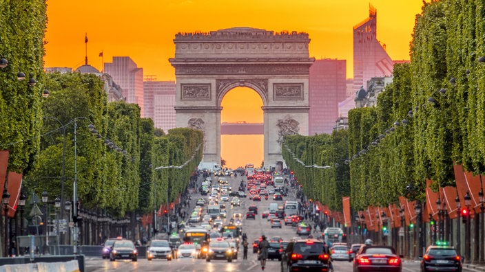 Vor dem Triumphbogen fahren Autos, die Straßenränder der Champs Elysees sind festlich beleuchtet