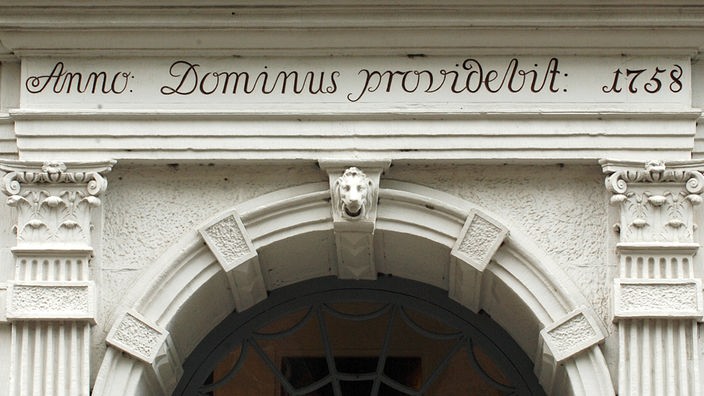Geschwungene Inschrift 'dominus providebit / Anno 1758' auf dem weißen Türsturz des Buddenbrook-Hauses.