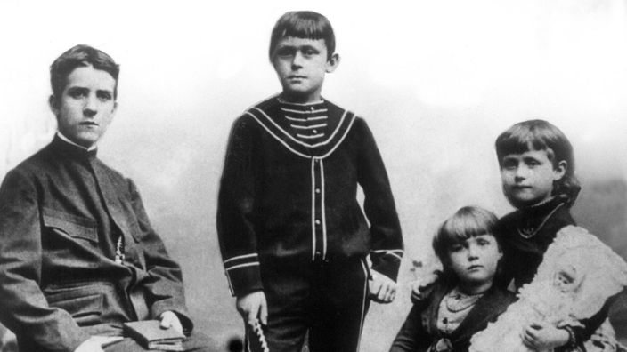 Schwarzweiß-Foto: Zwei Jungen - Heinrich links sitzend, Thomas in der Mitte im Matrosenanzug stehend – und zwei kleinere Mädchen im Kleid