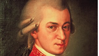 Das bekannteste Mozart-Porträt: Er trägt eine rote Jacke, steht seitlich vor einem dunklen Hintergrund und blickt den Betrachter an.