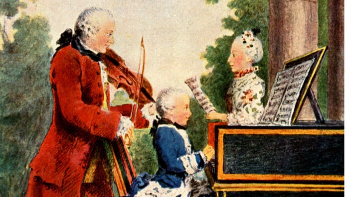 Der noch sehr kleine Mozart spielt Klavier, hinter dem Flügel steht seine Schwester mit einem Notenblatt und singt. Der Vater begleitet die beiden mit der Geige.