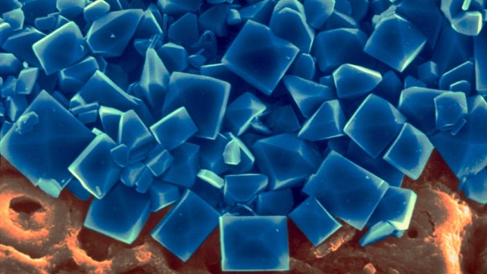 Elektronenmikroskopaufnahme von scheinbar blau gefärbtem Meersalz, dessen Kristallstruktur deutlich zu erkennen ist.