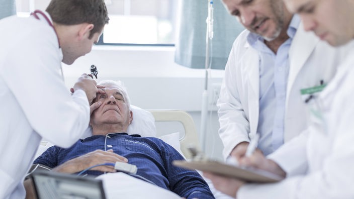 Ärzte am Krankenhausbett eines älteren Mannes.