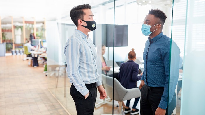 Zwei Männer mit Masken stehen in einer Tür und blicken sich an