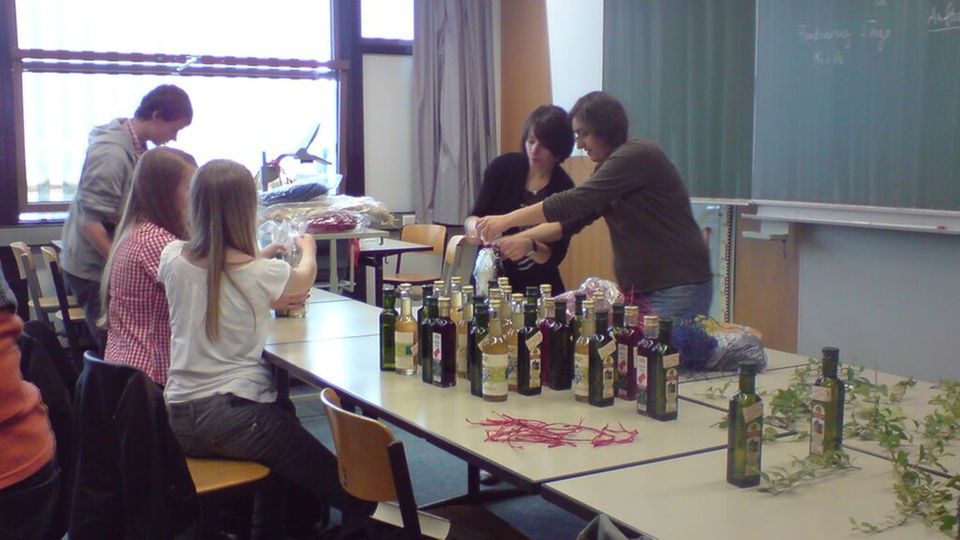 Schüler iverpacken Flaschen von Olivenöl in einem Klassenzimmer.