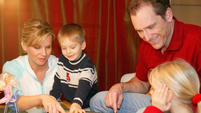 Eine Familie sitzt am Tisch und spielt ein Brettspiel.