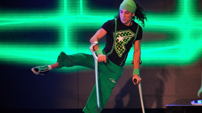 Der Akrobat Dergin Tokmak tanzt mit seinen Krücken bei einer Bühnenshow.
