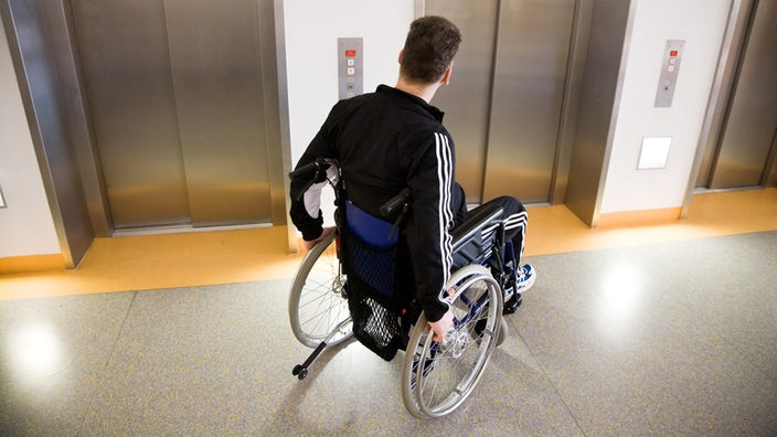 Rollstuhlfahrer vor einem Fahrstuhl