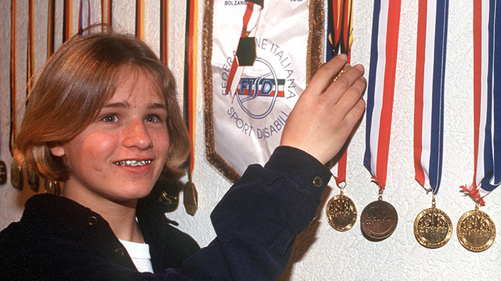 Die 15-jährige Verena Bentele vor einer Wand an der zahlreiche Medaillen hängen.
