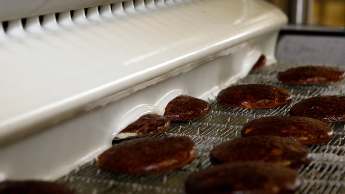 Zuckerguss fließt über frisch gebackene Lebkuchen auf einem Laufband in einer Fabrik