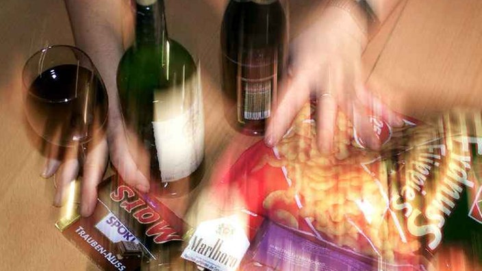 Verschwommenes Bild mit zwei Händen, die Weinflaschen, verschiedene Schokoriegel und Zigaretten von sich schieben. | Bildquelle: epd Verschwommenes Bild mit zwei Händen, die Weinflaschen, verschiedene Schokoriegel und Zigaretten von sich schieben.