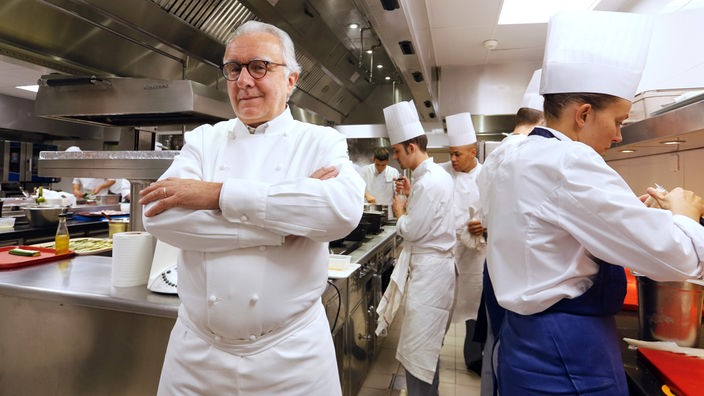 Alain Ducasse mit weiteren Köchen in einer Küche.