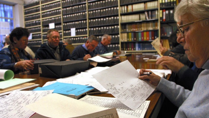Menschen sitzen lesend in einem Archiv