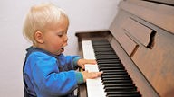Kleinkind spielt Klavier.