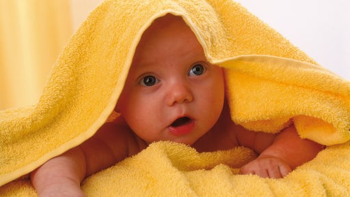 Baby guckt unter einem Handtuch hervor