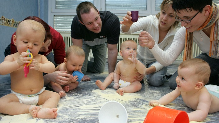 Eltern spielen mit ihren Babys im Rahmen eines PEKiP-Kurses 