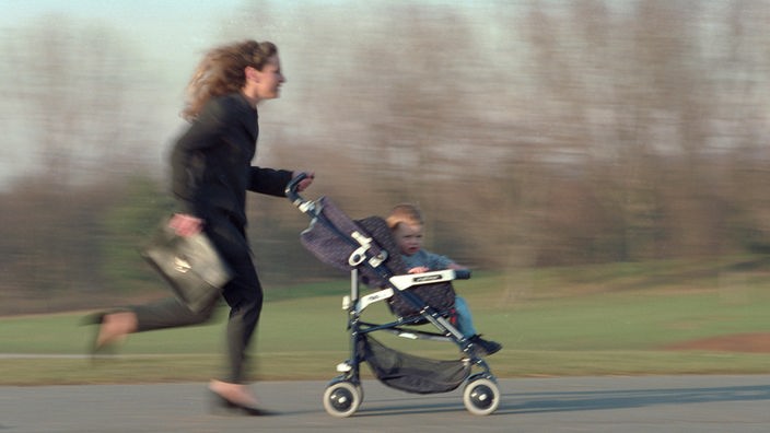 Frau joggt mit Kinderwagen.