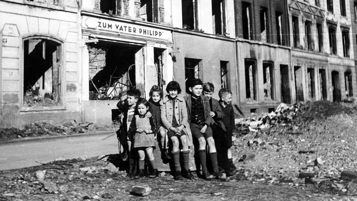 Kinder in einer zerstörten Straße nach Kriegsende 1945.