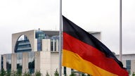Eine deutsche Flagge hängt vor dem Berliner Reichstag auf 'Halbmast'.