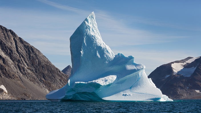 Ein strahlend weißer Eisberggipfel ragt aus dem dunklen Eismeer.