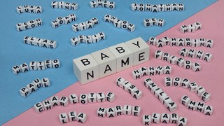 Buchstabenblöcke mit Babynamen auf blauem und rosa Untergrund