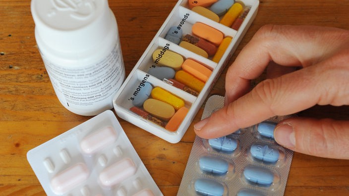 Eine Hand greift zu Tabletten gegen AIDS