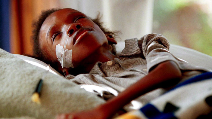 Ein aidskranker Junge liegt abgemagert in einem Krankenhausbett