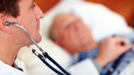 Ein Arzt hört mit Hilfe des Stethoskops die Herzgeräusche eines Patienten ab.